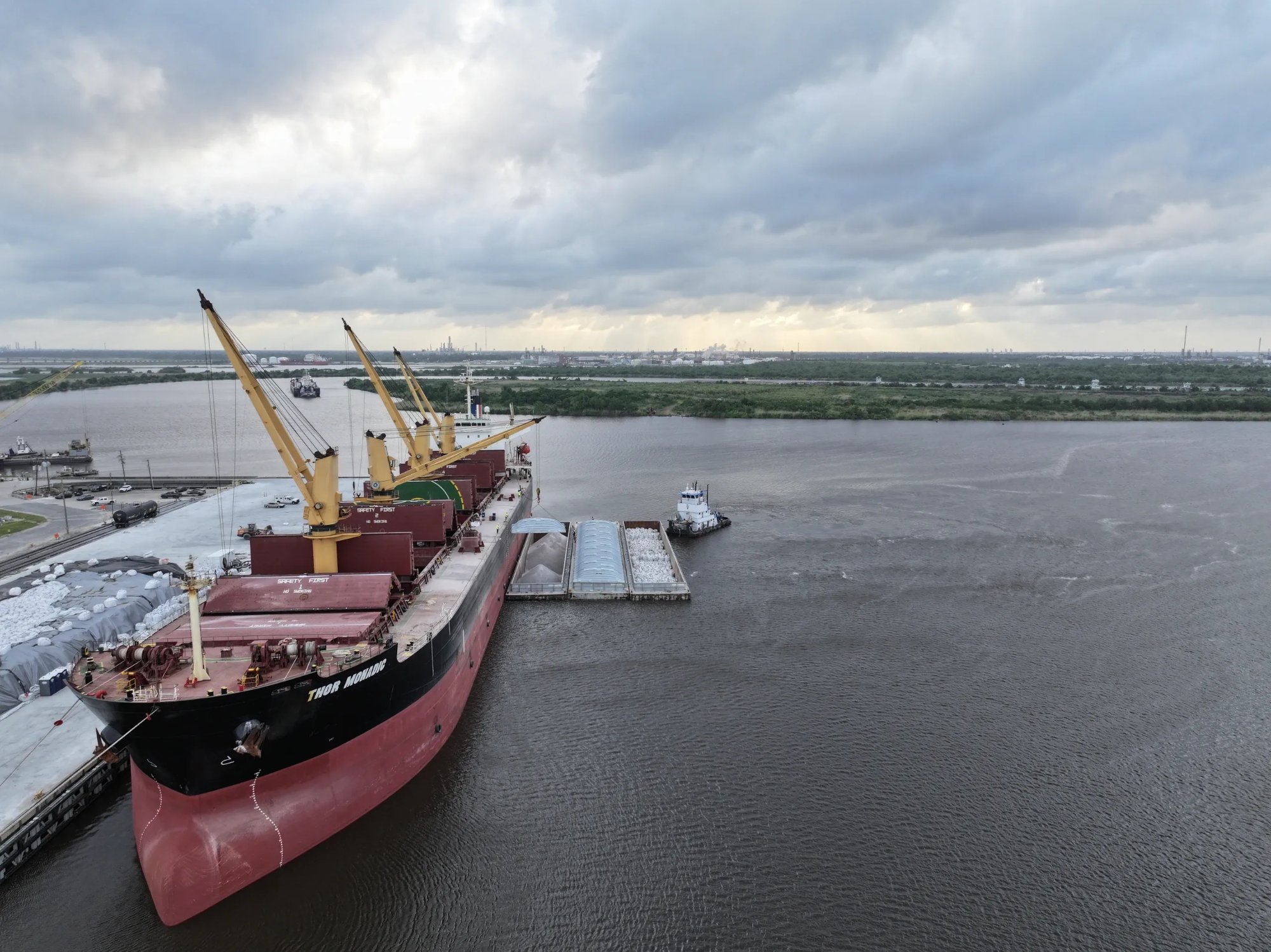 GCS supersack discharge vessel with barges alongside at Gulf Coast port — crane operations in progress