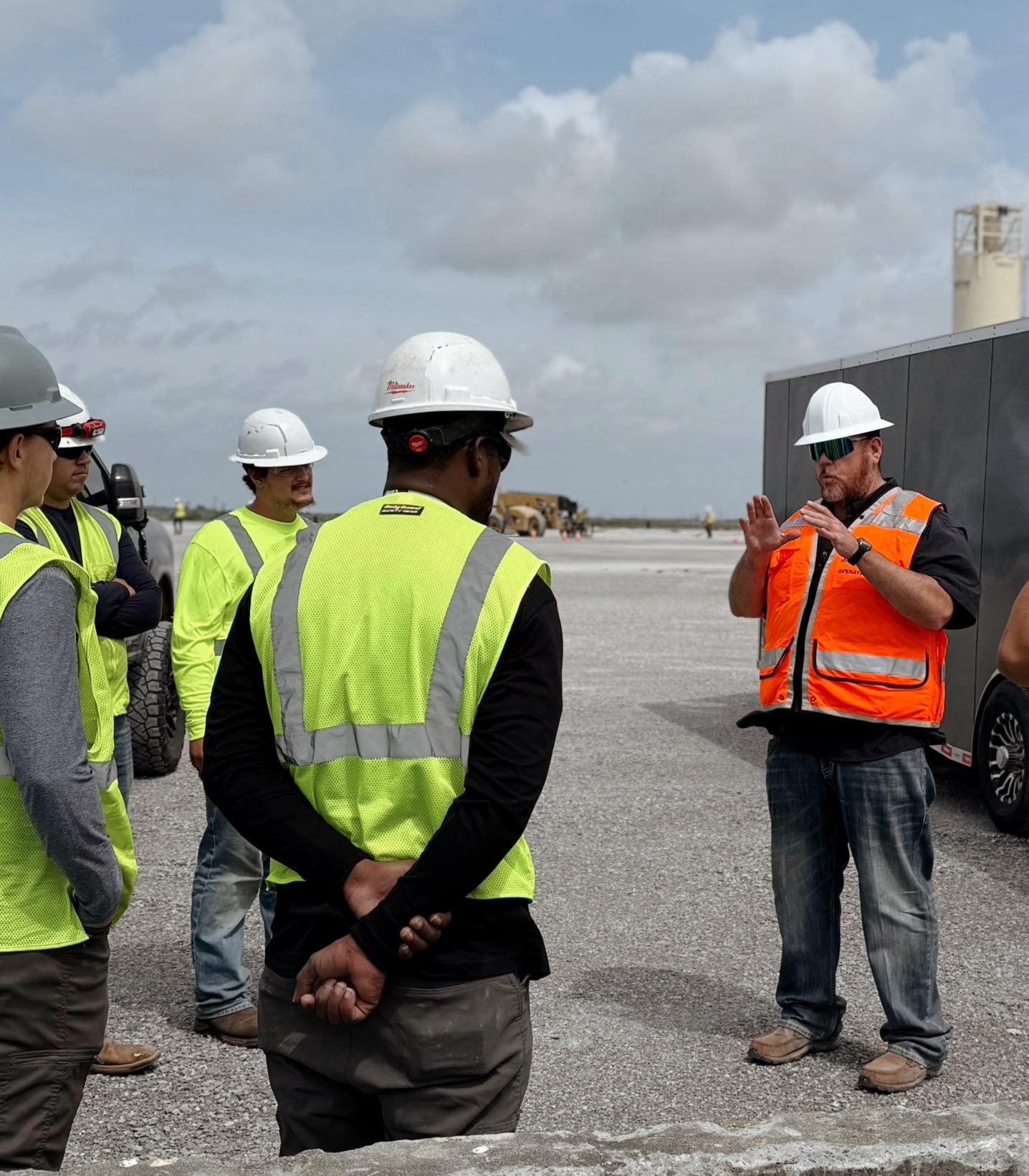 GCS crew pre-shift safety briefing at port — supervisor leading safety talk with crew in hi-vis and hard hats