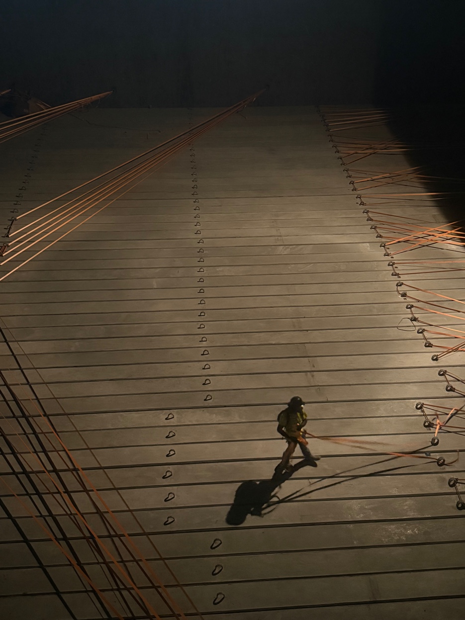 GCS stevedore working at night on concrete pile deck — rigging lines spread across the hold