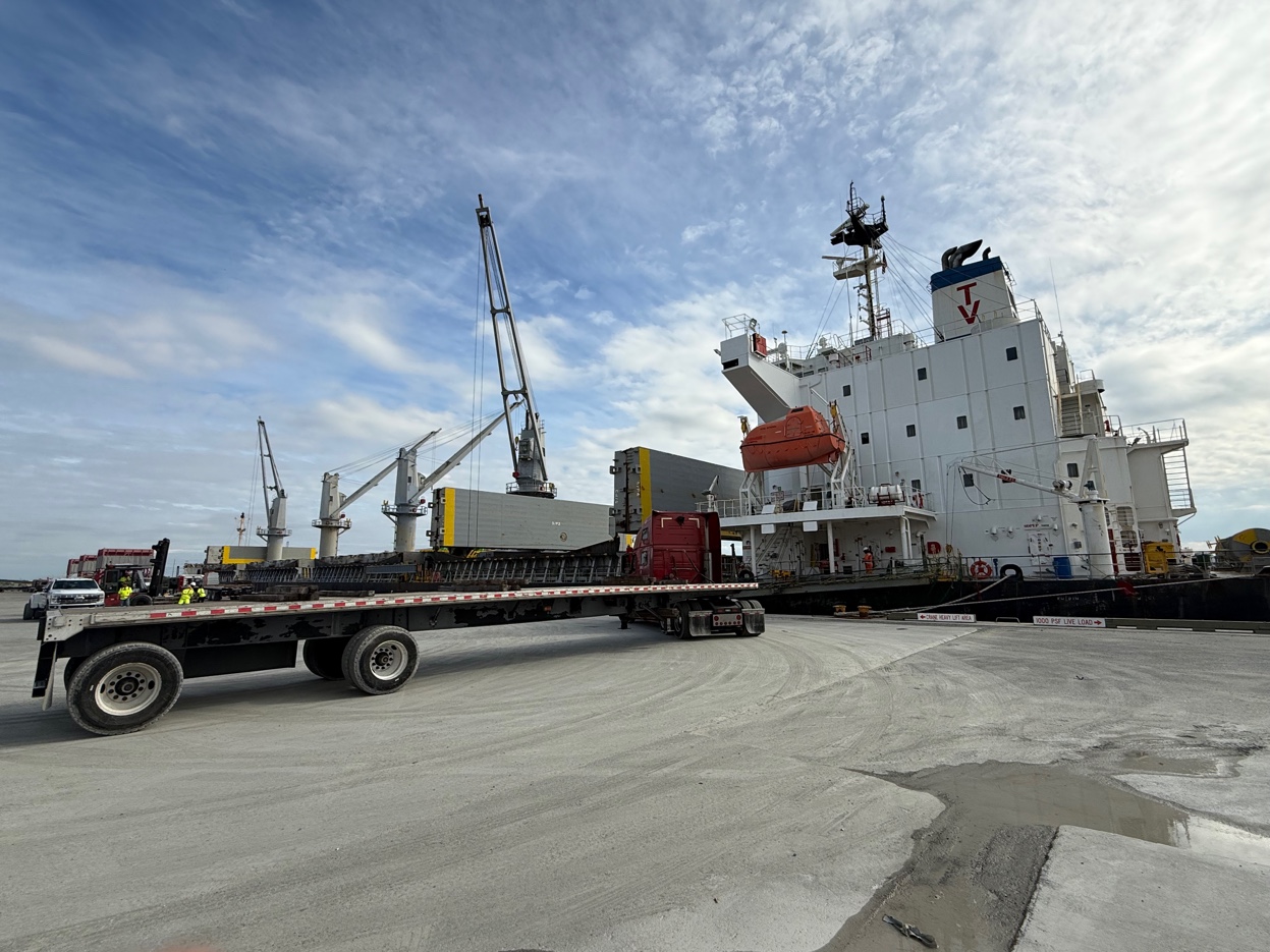 GCS Industrial Group port operations — vessel at berth with flatbed trucks and workers