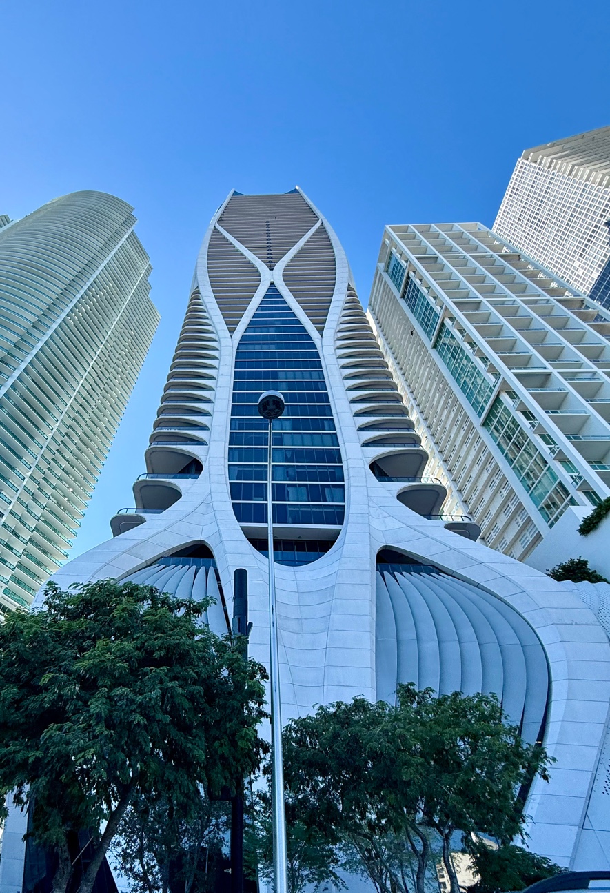 Miami Brickell modern architecture — distinctive futuristic tower rising above surrounding skyscrapers against blue sky